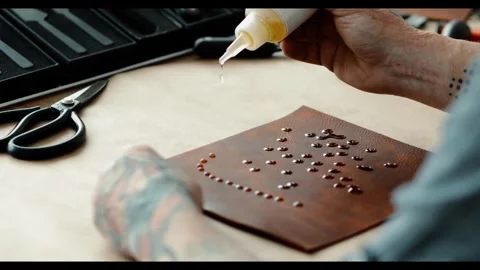 Craftsman applying drops of liquid oil to brown leather for crafting, close-up o 動画素材 299717112