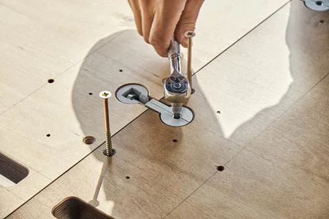 Craftsman assembles dining table turning worktop connector with wrench Stock Photos