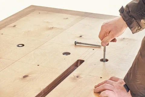 Craftsman assembles dining table turning bolts with hand Stock Photos