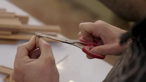 Craftsman assembling a miniature wooden frame with colorful stained glass p.. Видео 334740243