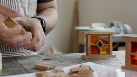 Craftsman assembling a miniature wooden frame with colorful stained glass p.. Stock Footage 334740545