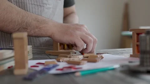 Craftsman assembling a miniature wooden frame with colorful stained glass p.. Vídeo Stock 334740546