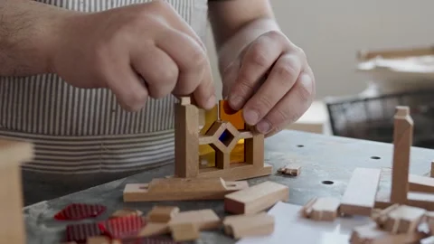 Craftsman assembling a miniature wooden frame with colorful stained glass p.. 스톡 동영상 334740643