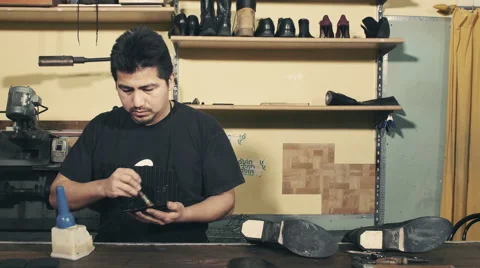 Craftsman brushing a rubber sole for a pair of boots with glue Stock Footage 61789632