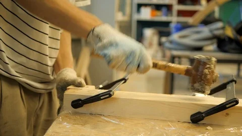 A craftsman in a carpentry workshop knocks with a rubber hammer on boards fas 動画素材 116313013