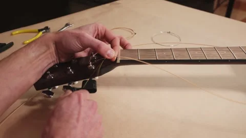Craftsman Changing Strings, Adjusting an Acoustic Instrument in a Home Workshop Stock Footage 329023937