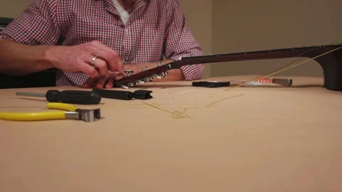 Craftsman Changing Strings and Tuning an Acoustic Guitar Stock Footage 329023943