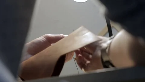 Craftsman create a brown leather wallet with his own hands with a needle, thr Stock Footage 82055768