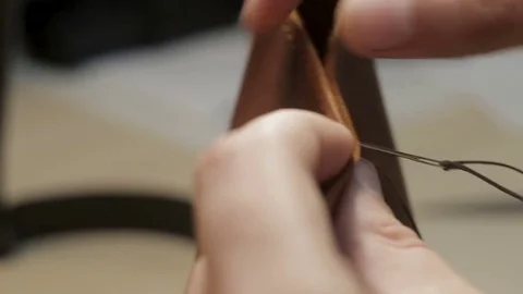 Craftsman create a brown leather wallet with his own hands with a needle, thr 스톡 동영상 82055830