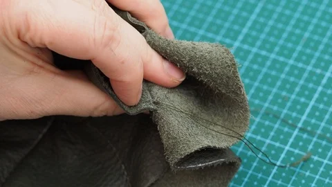 Craftsman cuts and fixes by fire the threads of stitches in the pouch bag Stock Footage 97415416