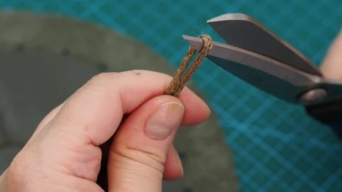 Craftsman cuts drawstring for pouch by scissors and fixes them by fire Stock Footage 97415547