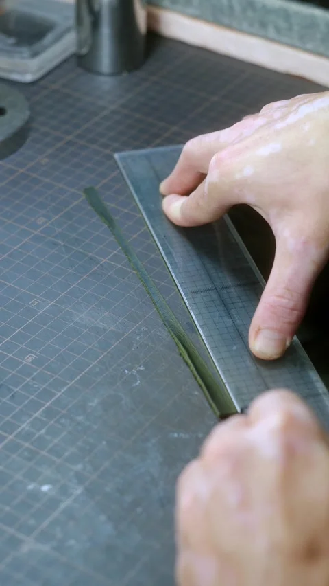 Craftsman cutting leather strip using ruler and cutter Stock Footage 296747576