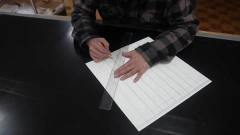 Craftsman drafting evenly spaced guide lines on white paper with a steel ruler Stock-Footage 342319392