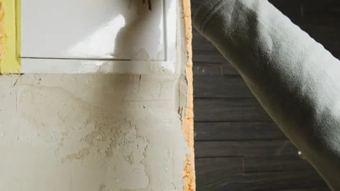 Craftsman evens out layers of plaster on wall during renovation Stock Footage 304411130