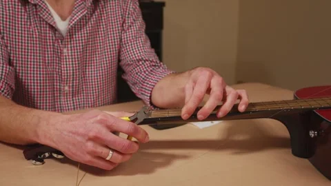 Craftsman Expertly Changing Strings on an Acoustic Guitar in a Home Workshop Stock Footage 329023918