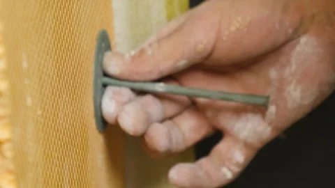 Craftsman fastens foam board using hammer during renovation Stock Footage 304411915
