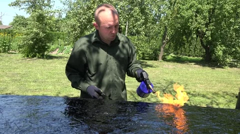 Craftsman with flame from torch tool lay tar resin on boat bottom. 4K Stock Footage 57134454