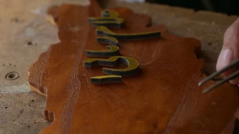 Craftsman hands accurately and precisely placing Arabic letters on wooden Stock Footage 244726992