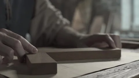 Craftsman hands verifying lines on parchment paper with a wooden square ruler 스톡 동영상 339231879