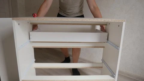 The craftsman inserts a shelf into the chest of drawers Stock Footage 318420885