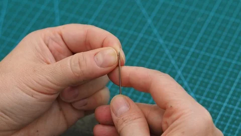 Craftsman inserts thread in needle eye  and fixes stitches of a pouch Stock Footage 97415426