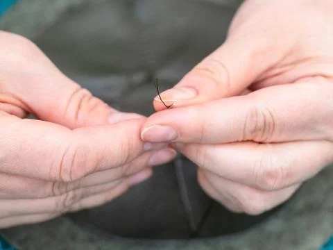 Craftsman inserts thread in needle to sew a pouch Stock Photos