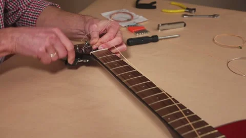 Craftsman Maintaining Acoustic Guitar: Installing New Strings Preparing for Play Stock Footage 329023944