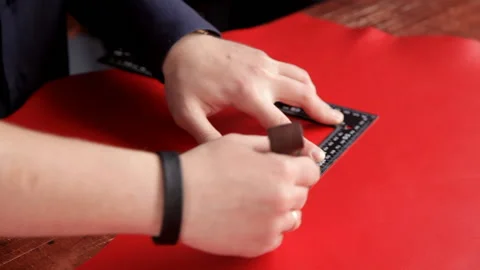 Craftsman makes a line of markings on the red leather cloth Stock Footage 88840264
