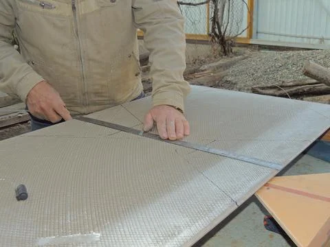 A craftsman measures the width of a large tile from the back side Stock Photos