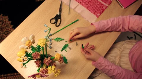 Craftsman meticulously assembling vibrant floral bouquet on wooden table Stock Footage 335780350