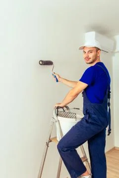Craftsman in overall standing on scale while mixing color in bucket Stock Photos