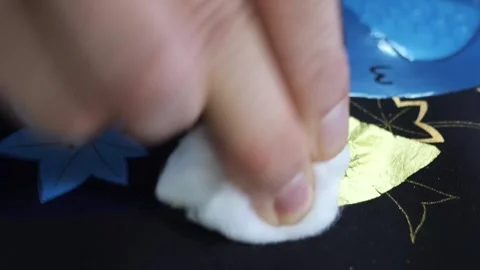 Craftsman presses a gold leaf sheet with a cotton pad onto the edge of a blue Vídeos de archivo 339123577