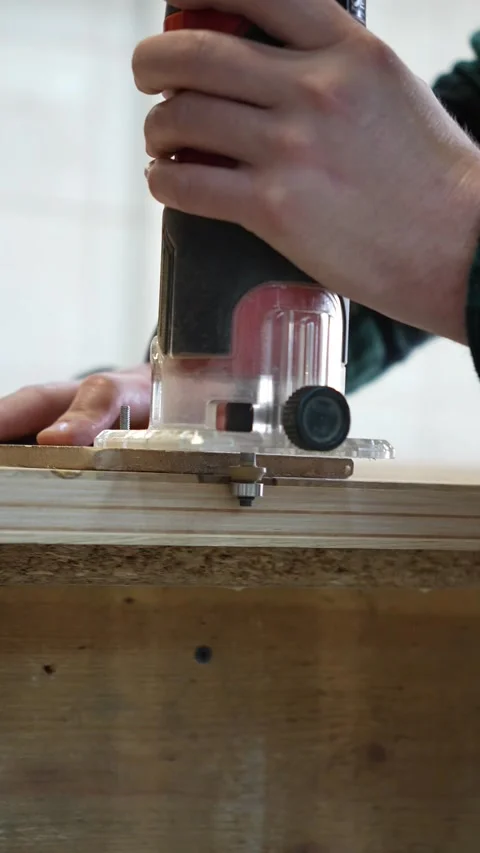 A craftsman processes the end of a panel with a hand milling cutter Stock Footage 317414705