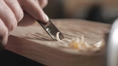 A craftsman processes a pine wood board with a chisel. artisan makes a tea tray Stock Footage 156670546