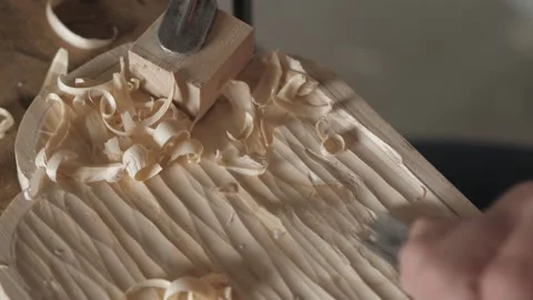 A craftsman processes a pine wood board with a chisel. artisan makes a tea tray Stock Footage 156670553
