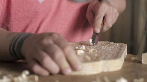 A craftsman processes a pine wood board with a chisel. artisan makes a tea tray Stock Footage 156670621