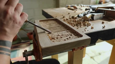 A craftsman processes a walnut board with a chisel. artisan makes a tea tray. Stock Footage 144244072