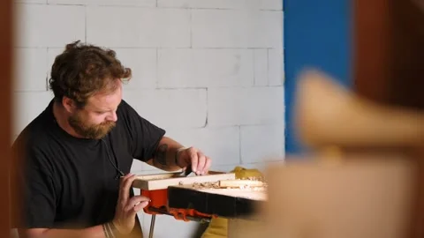The craftsman processes the walnut board with a small planer. artisan makes a Stock Footage 144244226