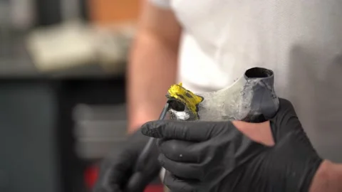 Craftsman remoiving plastic material from prosthesis in factory Stock Footage 236623920