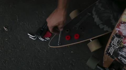 Craftsman repairs the longboard with a wrench to replace kingpin and bushing Stock Footage 163365180