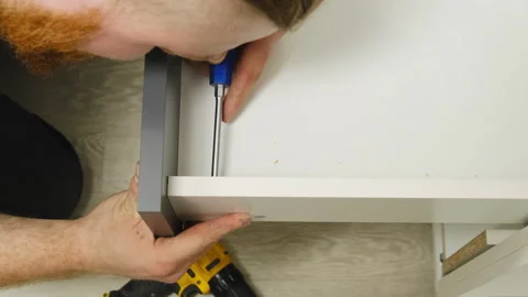 Craftsman with screwdriver in hands finishes assembling drawer Video stock 316188855