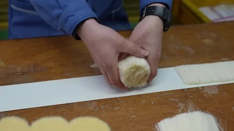 Craftsman shaping a bundle of cream coloured bristles on a white sheet of paper 動画素材 347123878
