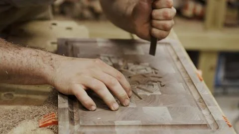 Craftsman skillfully uses a chisel to shape a beautiful wooden board Stock Photos