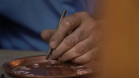 Craftsman strikes patterns on copper vessels with a hammer in his hand Stock-Footage 329392873