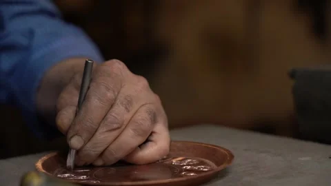 Craftsman strikes patterns on copper vessels with a hammer in his hand Video stock 329392886