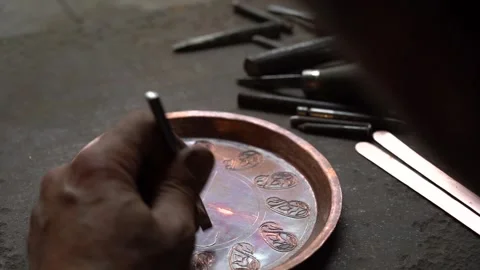 Craftsman strikes patterns on copper vessels with a hammer in his hand 스톡 동영상 329392888