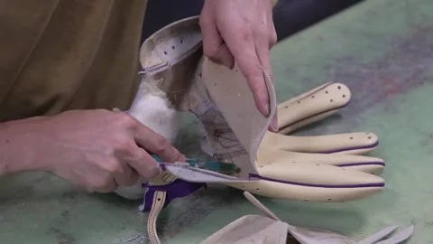 Craftsman stuffing padding and gluing inside a purple trimmed baseball glove Stock Footage 340565758