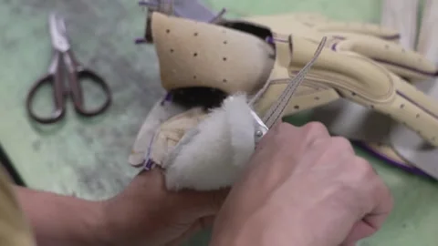 Craftsman stuffing soft cotton wadding into a baseball glove finger with Stock Footage 340156161