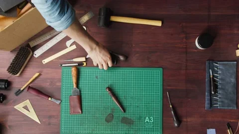 Craftsman taking his instruments from workplace after repairing leather things Stock Footage 157374622
