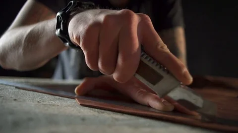 Craftsman with tattoos cutting leather with a sharp knife and a ruler Stock Footage 71503645